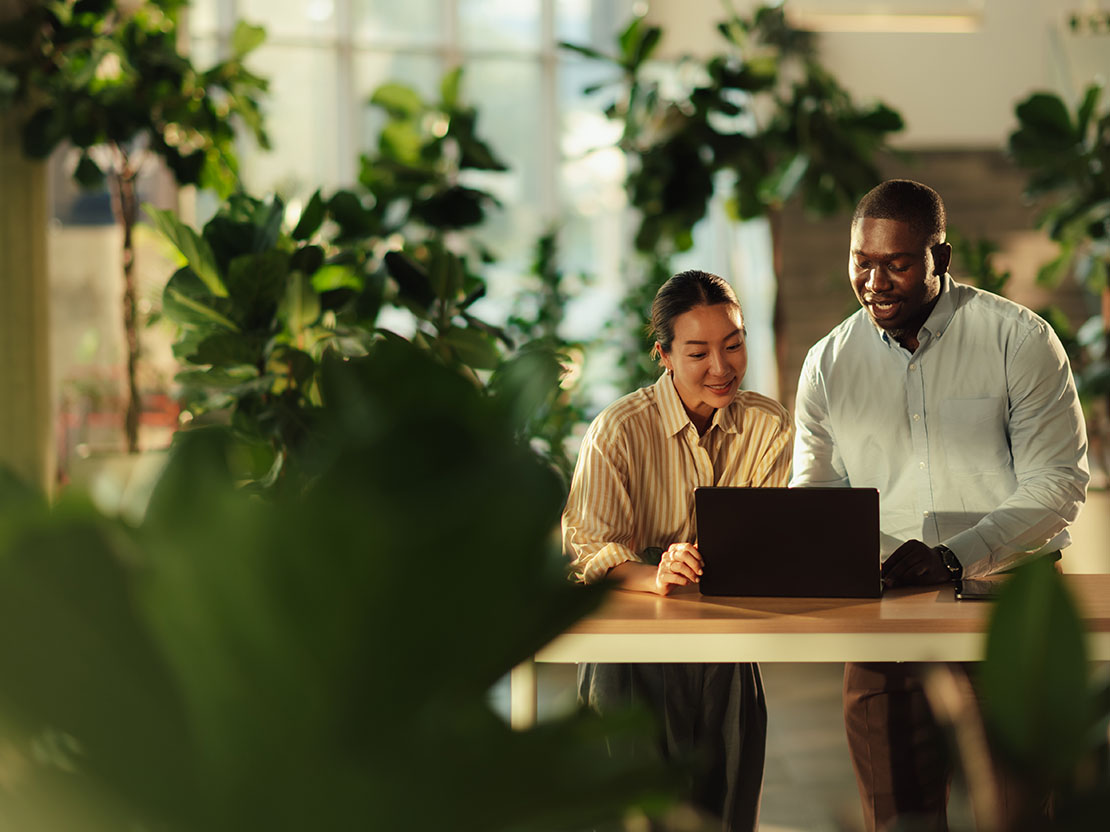 Två personer arbetar vid laptop omgivna av gröna växter