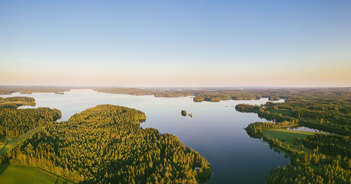 Flygfoto över skogigt, nordiskt landskap i soluppgång