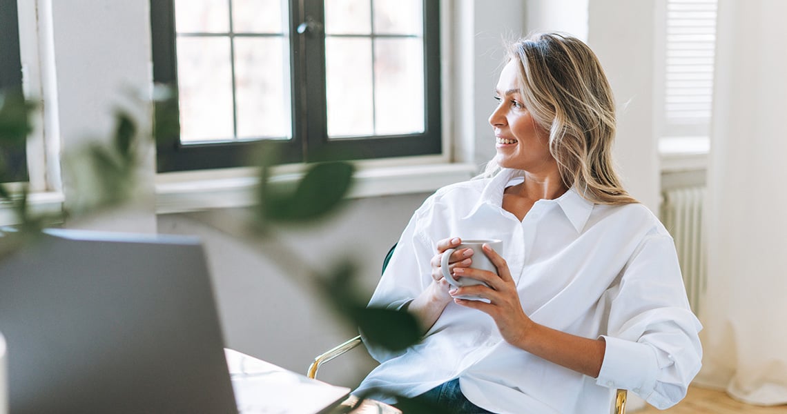 Kvinna i vit blus tittar ut genom fönstret