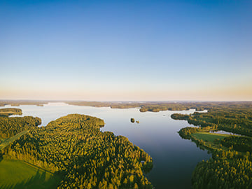 Flygfoto över skogigt, nordiskt landskap i soluppgång